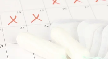 Tampons et serviettes hygiéniques posés sur un calendrier marqué de croix rouges.