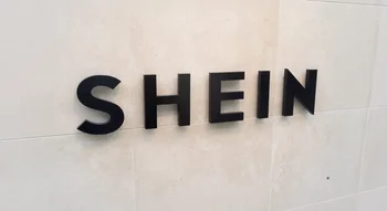 Logo Shein en lettres noires sur un mur beige.