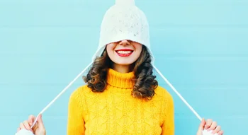 Femme souriante en pull jaune et bonnet blanc, symbole de bien-être et de santé intime.