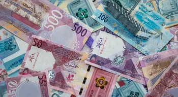 مجموعة متناثرة من الأوراق النقدية للريال القطري بفئات مختلفة مثل 500 و 100 و 50 ريالاً، تعرض تصاميمها الملونة وتفاصيلها الدقيقة.