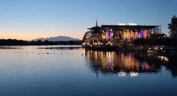 Vue nocturne du Casino Barrière Enghien-les-Bains, avec des lumières colorées se reflétant sur le lac.