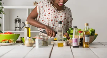 Femme préparant un repas avec des légumes frais, alimentation pour booster sa fertilité.