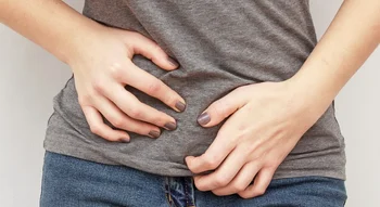 Femme tenant son bas-ventre avec les mains, exprimant une gêne ou une douleur.