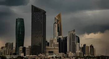 أفق مدينة الكويت مع ناطحات سحاب حديثة مثل برج الحمراء، تطل على المياه تحت سماء داكنة وعاصفة.