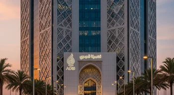 واجهة مبنى مصرف أبوظبي الإسلامي (ADIB) بتصميمه المعماري المزخرف بأنماط هندسية، تبرز علامة المصرف المضيئة فوق المدخل الرئيسي وقت الغروب، وتحيط به أشجار النخيل.