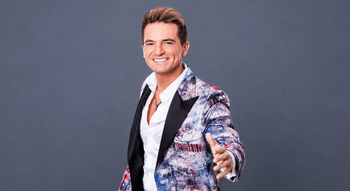 Jorge Guerreiro sorri de blazer estampado e camisa branca