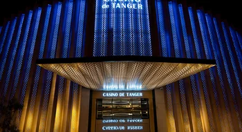 الواجهة المضيئة لكازينو طنجة ليلاً، تتميز بأضواء عمودية زرقاء وتصميم هندسي ذهبي فوق المدخل الرئيسي.