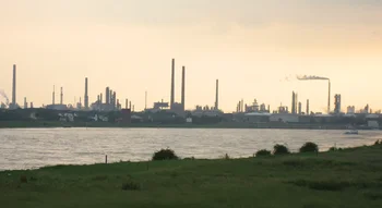 Paysage industriel avec usines et cheminées représentant l’Industrie moderne près d’un fleuve.