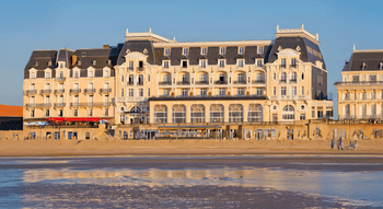 Vue extérieure de l'hôtel et Casino de Houlgate, en bord de mer, avec des reflets sur le sable mouillé.