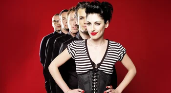 Les membres de Superbus alignés derrière Jennifer Ayache sur fond rouge.