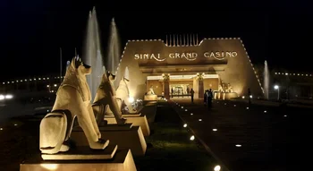 الواجهة المضاءة لكازينو سيناء جراند ليلاً، تتميز بتماثيل على الطراز المصري القديم ونوافير مياه تزين الممر المؤدي للمدخل.