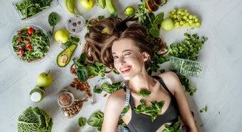 Jeune femme entourée d’aliments végétaux nutritifs, illustrant les raisons de devenir végétarien ou végétalien pour la santé.