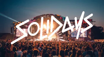Scène principale illuminée de Solidays au crépuscule avec logo géant.