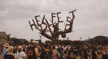Sculpture d’arbre rouillé épelant Hellfest parmi les festivaliers.