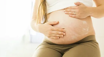 Femme enceinte appliquant de la crème sur son ventre pour prévenir les vergetures de grossesse.