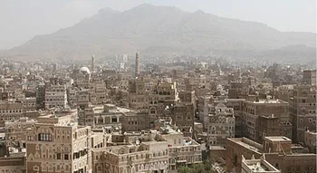 مدينة صنعاء (Sana'a City): مشهد بانورامي للمباني التاريخية في صنعاء القديمة مع جبال في الخلفية.