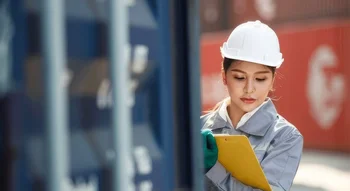 موظفة لوجستية تؤدي إحدى مهام المخلص الجمركي من خلال فحص المستندات بجانب حاوية شحن في الميناء.