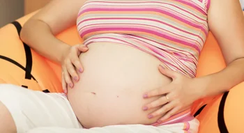 Femme enceinte touchant son ventre, possible ressenti des contractions de Braxton-Hicks.