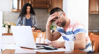 Homme préoccupé devant un ordinateur en pensant au recouvrement amiable des créances.