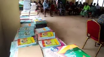 Piles de manuels et fournitures lors de la cérémonie où 45 élèves parrainés par la coopération Évreux-Djougou reçoivent des kits scolaires.