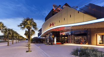 Entrée élégante du Casino Barrière Bordeaux, illuminée de nuit, avec des palmiers décoratifs.