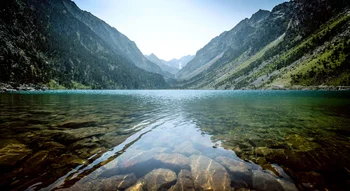 Le Lac de Gaube entouré de montagnes verdoyantes et roches.