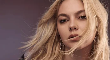 Portrait artistique de Louane, cheveux blonds au vent, sur fond sombre.