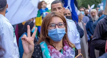 La garde à vue de Kenza Khattou – jeune femme manifestant pacifiquement, main levée en signe de paix.