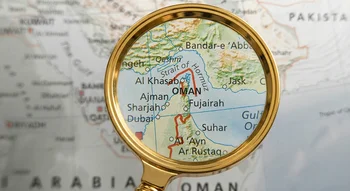 عدسة مكبرة تسلط الضوء على موقع مضيق هرمز الاستراتيجي على خريطة جغرافية.