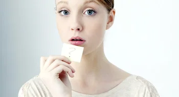 Femme tenant un post-it avec un point d’interrogation, exprimant des questions courantes sur le cycle menstruel.