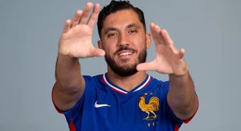 Rayan Cherki souriant avec le maillot de l’équipe de France.