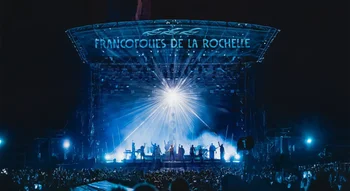 ue aérienne de la scène des Francofolies de La Rochelle illuminée la nuit, avec un public en liesse.