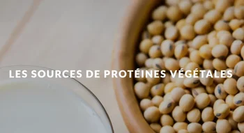 Bol rempli de graines de soja à côté d'un verre de lait végétal, riches sources de protéines végétales.