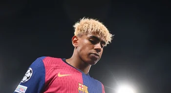 لاعب كرة القدم لامين يامال يرتدي قميص نادي برشلونة مع شعار دوري أبطال أوروبا تحت أضواء الملعب.