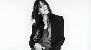 Charlotte Gainsbourg en portrait artistique en noir et blanc, vêtue d'une veste élégante.
