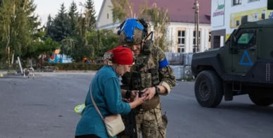 Soldat ukrainien aidant une civile durant la guerre en Ukraine.