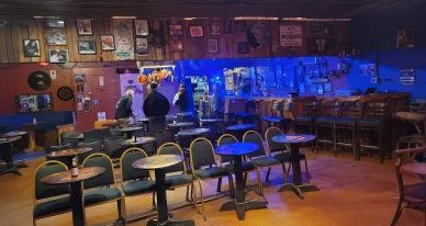Intérieur du Bradfordville Blues Club avec tables, bar et décor vintage.