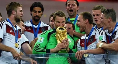 الحارس مانويل نوير يقبل كأس العالم الذهبي بحماس بينما يحيط به لاعبو المنتخب الألماني للاحتفال بالفوز بمونديال 2014