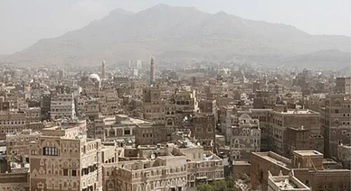 مدينة صنعاء (Sana'a City): مشهد بانورامي للمباني التاريخية في صنعاء القديمة مع جبال في الخلفية.