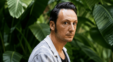 Samuel Úria em retrato junto a plantas tropicais
