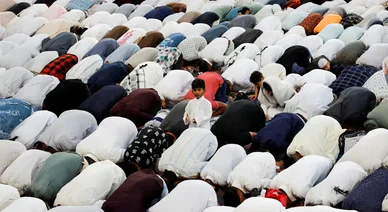 طفل صغير يقف وسط صفوف المصلين الساجدين أثناء أداء صلاة العيد.