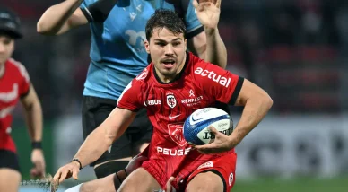 Antoine Dupont en action avec le Stade Toulousain en maillot rouge.