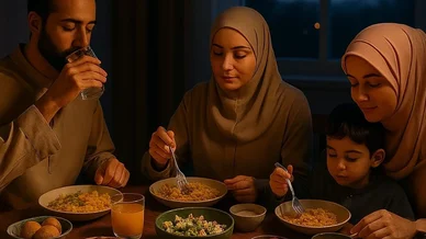 عائلة مسلمة ترتدي الزي التقليدي تتناول وجبة الإفطار معًا على طاولة مليئة بأطعمة رمضان