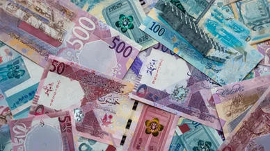 فئات متنوعة من الأوراق النقدية للريال القطري مجموعة متناثرة من الأوراق النقدية للريال القطري بفئات مختلفة مثل 500 و 100 و 50 ريالاً، تعرض تصاميمها الملونة وتفاصيلها الدقيقة.