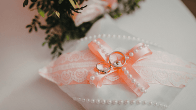 Золоті обручки, що лежать на декоративній весільній подушечці