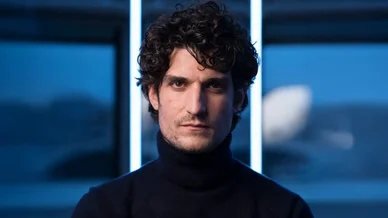Louis Garrel en portrait serré dans une lumière bleutée moderne.