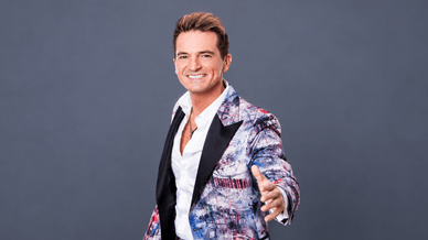 Jorge Guerreiro sorri de blazer estampado e camisa branca
