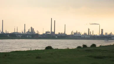 Paysage industriel avec usines et cheminées représentant l’Industrie moderne près d’un fleuve.