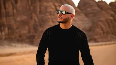 DJ Snake : Une silhouette stylée sous le soleil du désert. DJ Snake posant fièrement dans le désert avec des montagnes en arrière-plan.