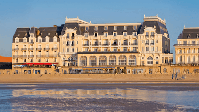 Vue extérieure de l'hôtel et Casino de Houlgate, en bord de mer, avec des reflets sur le sable mouillé.